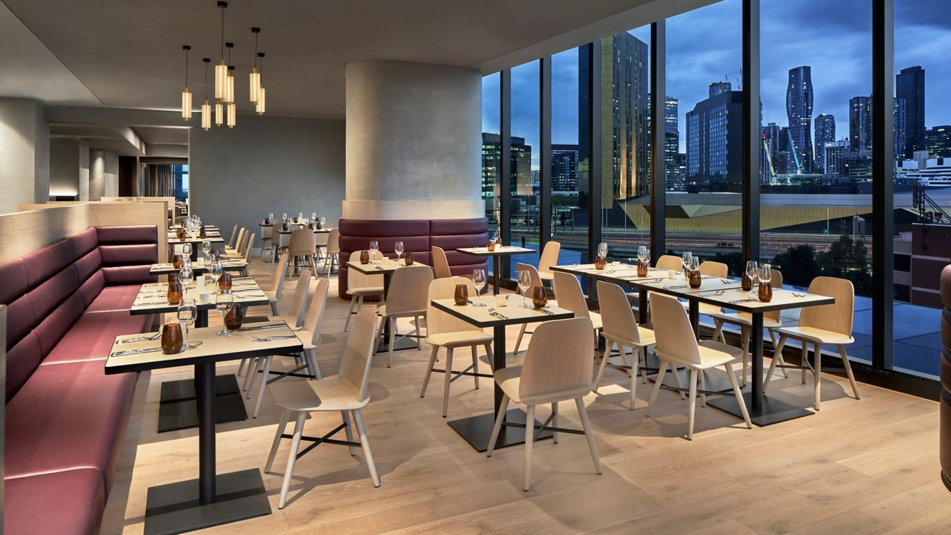 Hotel restaurant area featuring custom veneered tables and benches, with columns wrapped in burgundy leather.