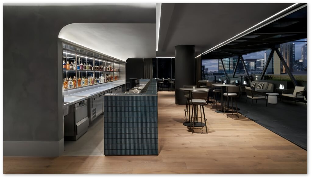 Hotel restaurant bar with a blue tiled bar, custom back bar wall neatly displaying a variety of red wines, and bar tables, chairs, and sofas in front.